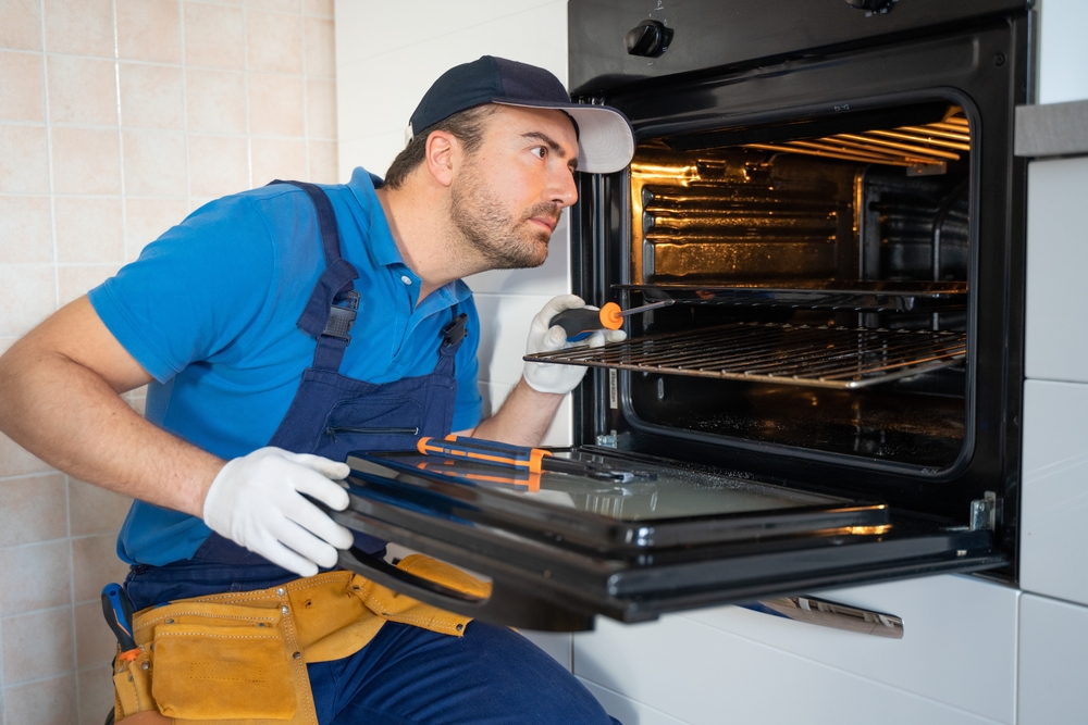 One,Repairman,Fixing,Malfunctioning,Kitchen,Oven,Problem